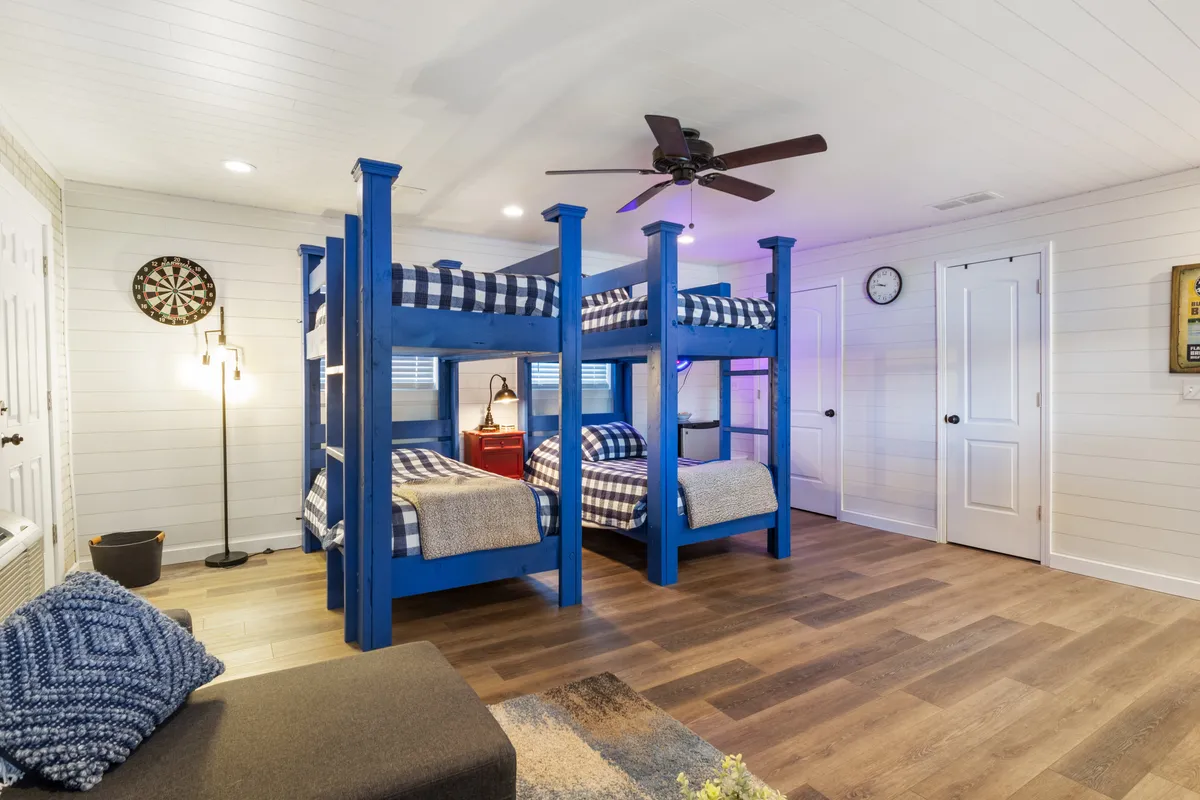 This cheerful, multi-purpose room showcases bunk beds, a dartboard, a sofa, and family-friendly decor. It feels welcoming and playful, with areas designed for both resting and engaging in games or storytelling.