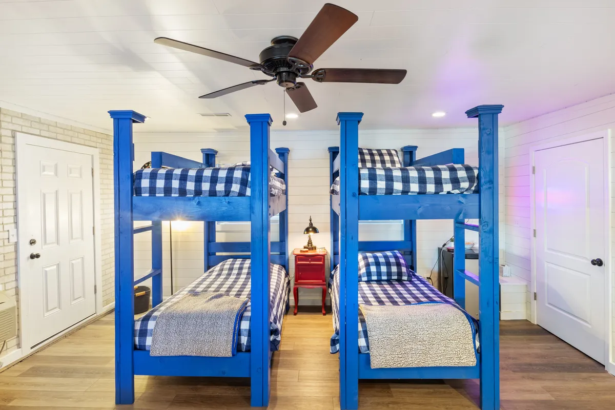 A bright bunk room scene focusing on bunk beds, a red nightstand, and playful elements such as a ceiling fan. The inviting setup hints at imaginative activities like pillow fights and late-night storytelling.