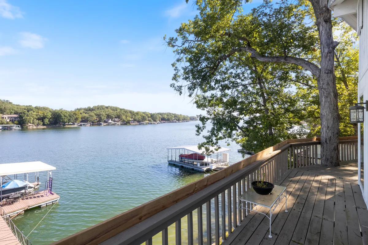 A peaceful lakeside view featuring docks, a wooden deck, and a tree providing partial shade. The dock extends into the water, ideal for fishing or boat launching, while the expansive lake stretches out into the distance, promising exploration and adventure.